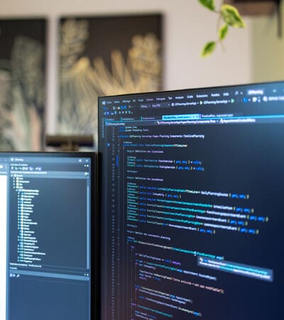 illustration prestation logiciel sur mesure deux ecrans avec des lignes de code