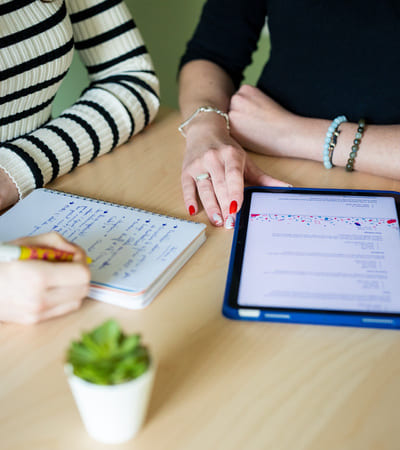 illustration prestation naming représenté par deux femme assise sur une table l'une qui ecrit et l'autre sur une tablette apple