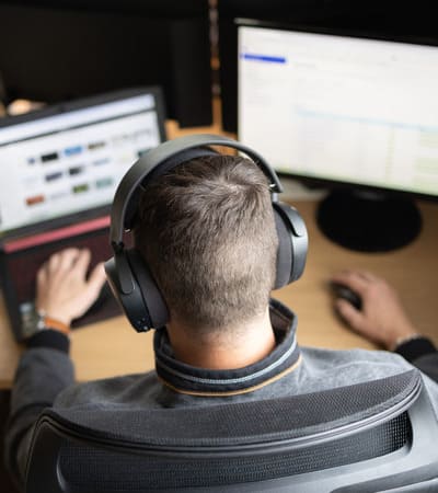 illustration prestation site internet vitrine e-commerce homme devant deux ecrans d'ordinateur avec un casque